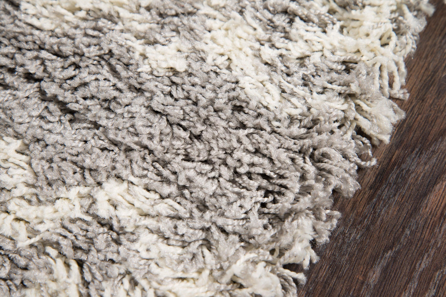Shaggy rug in gray and cream tones with a long-pile texture on dark wood floor.
