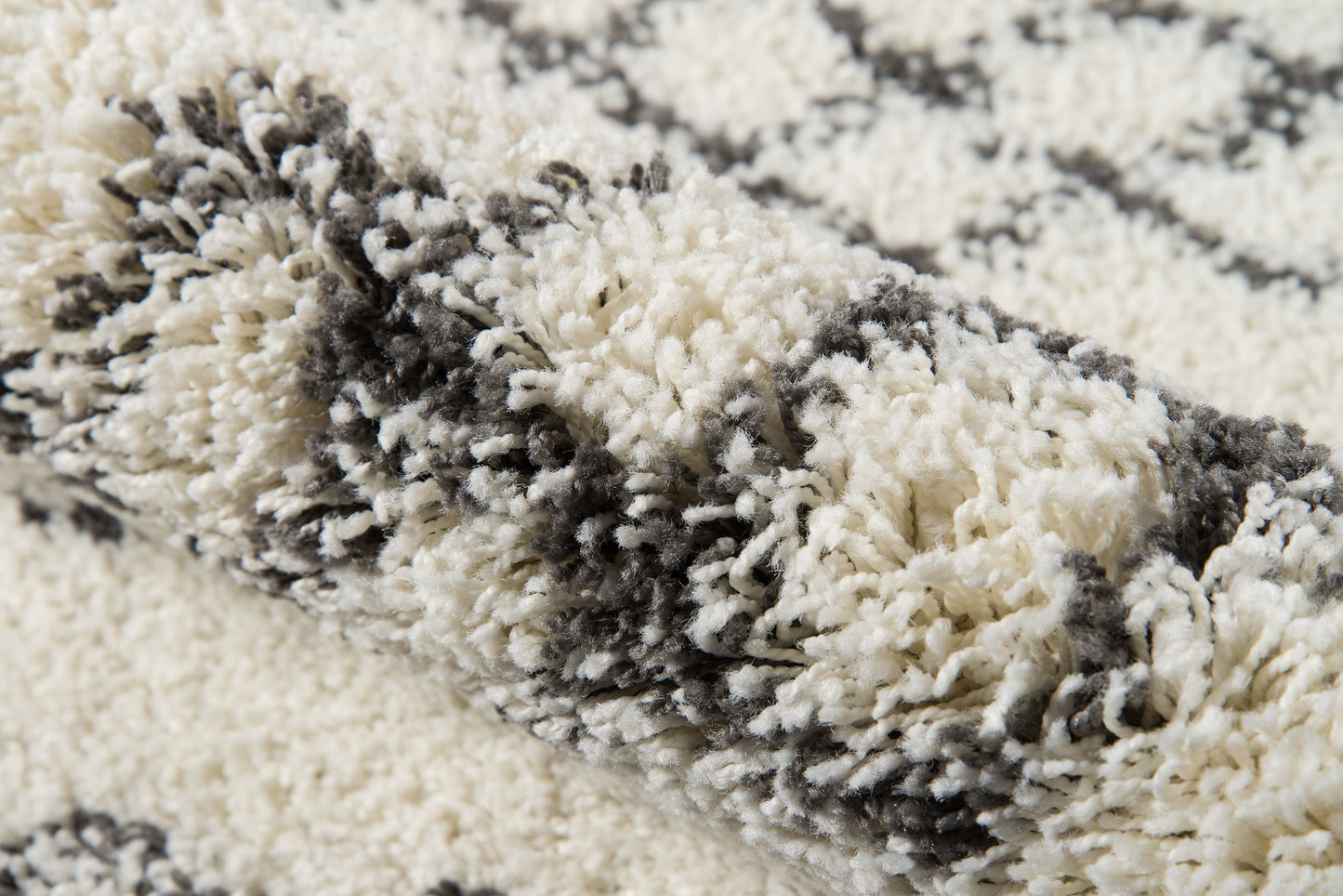 Cream and gray high-pile shag rug with plush fibers in an abstract striped pattern.