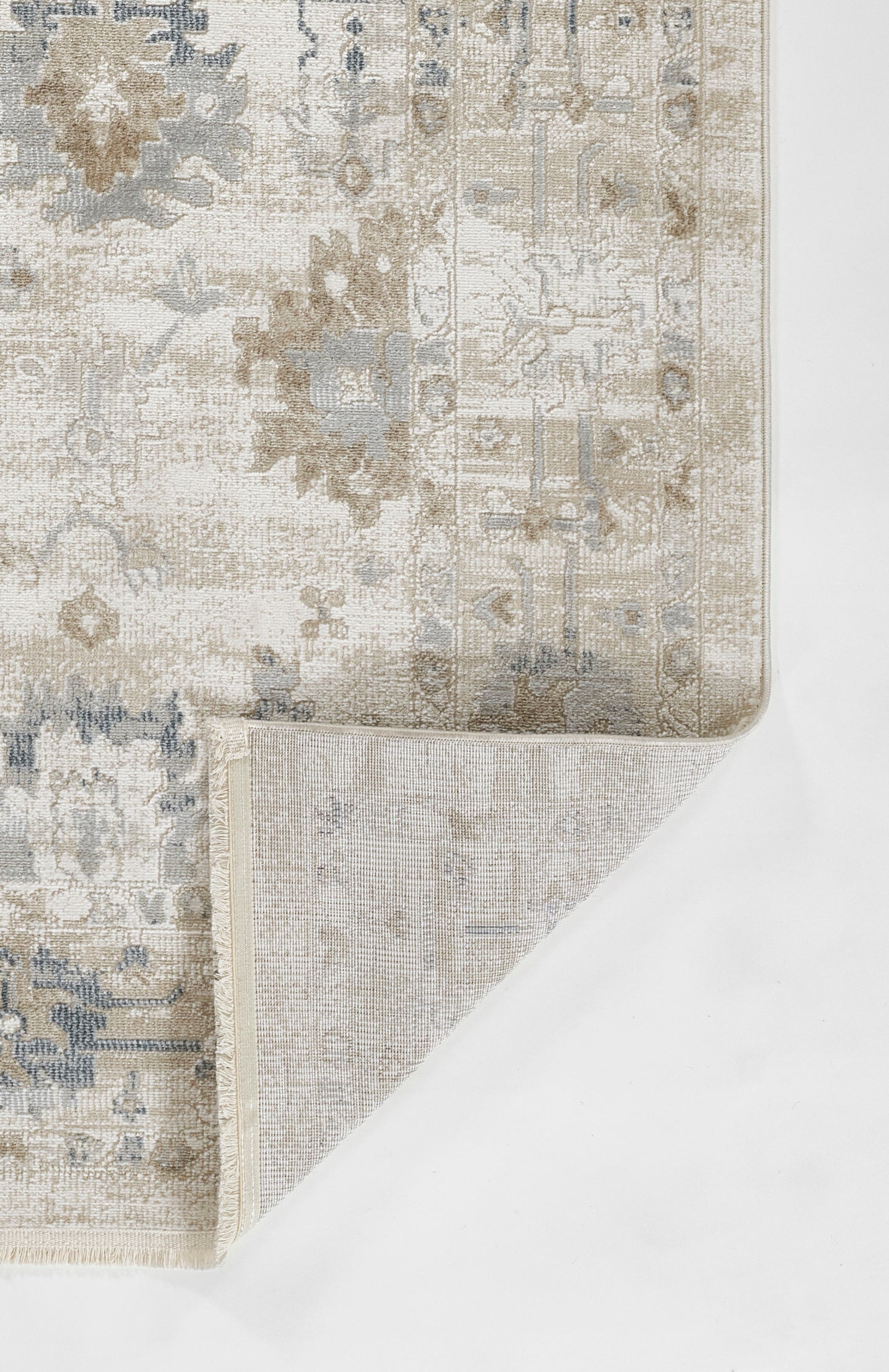 Rectangular distressed oriental rug in ivory & beige & blue-gray with floral medallion; folded corner shows underside.