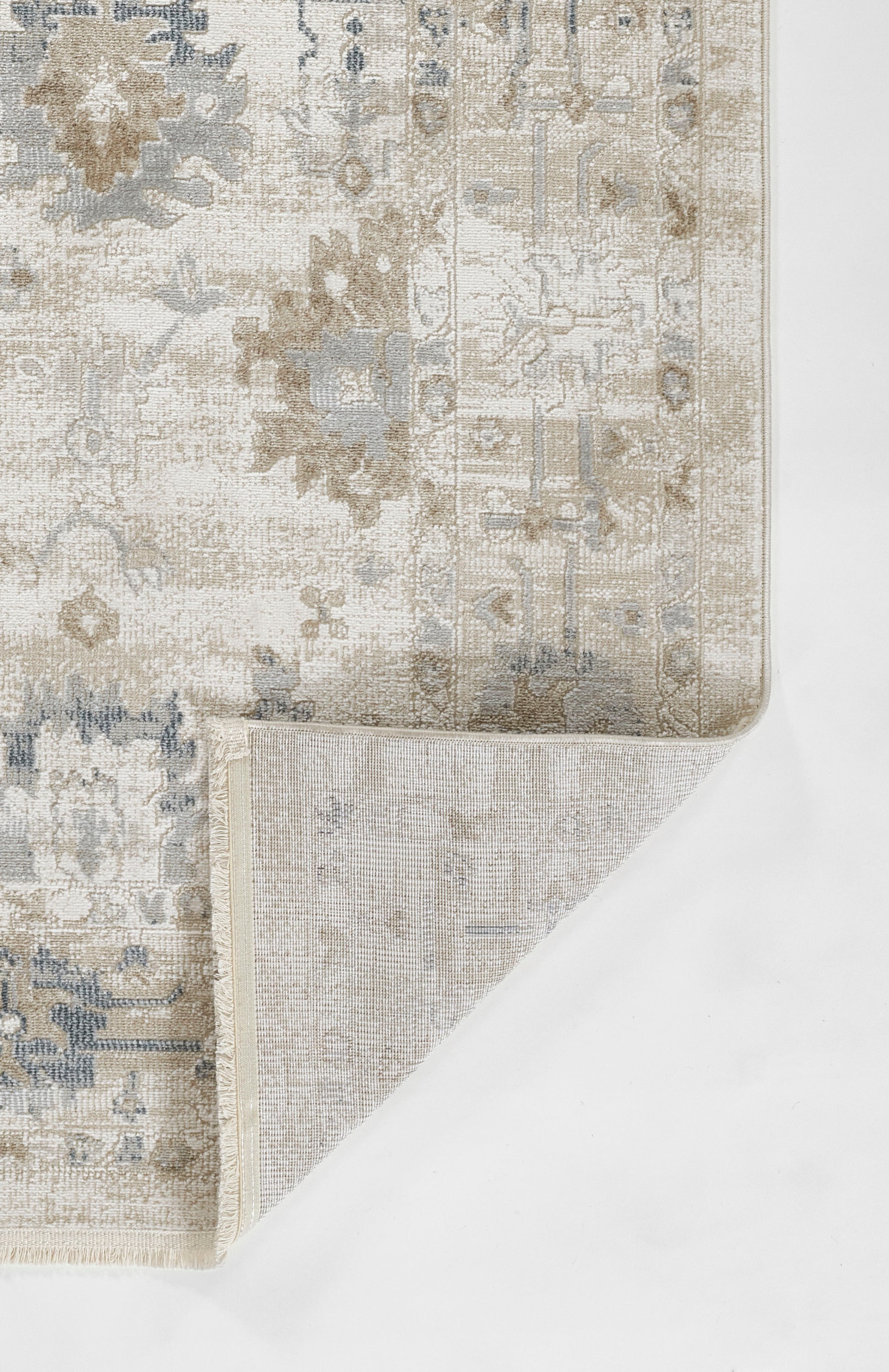 Rectangular distressed oriental rug in ivory & beige & blue-gray with floral medallion; folded corner shows underside.