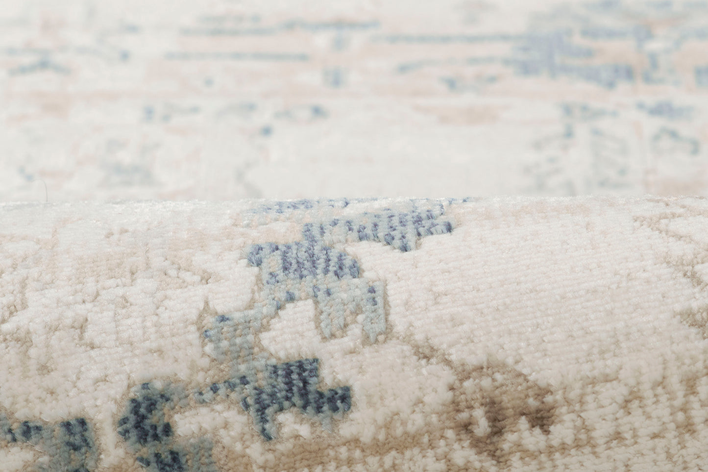 Cream rug with light blue geometric motifs and plush, textured pile; close-up detail.