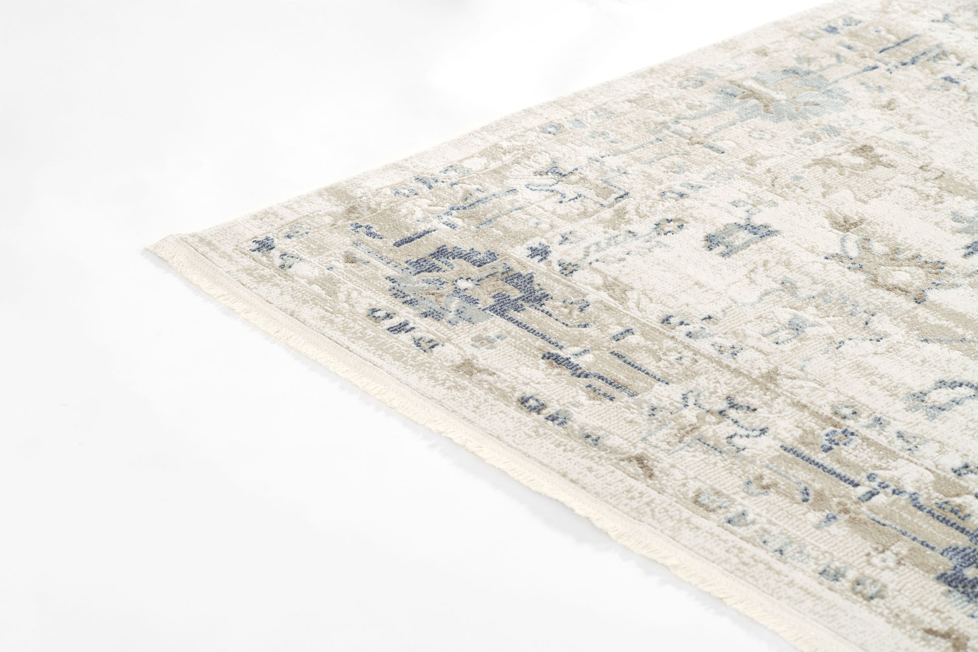 Beige distressed area rug with muted blue floral pattern & fringe edge; rectangular, cozy living room rug.