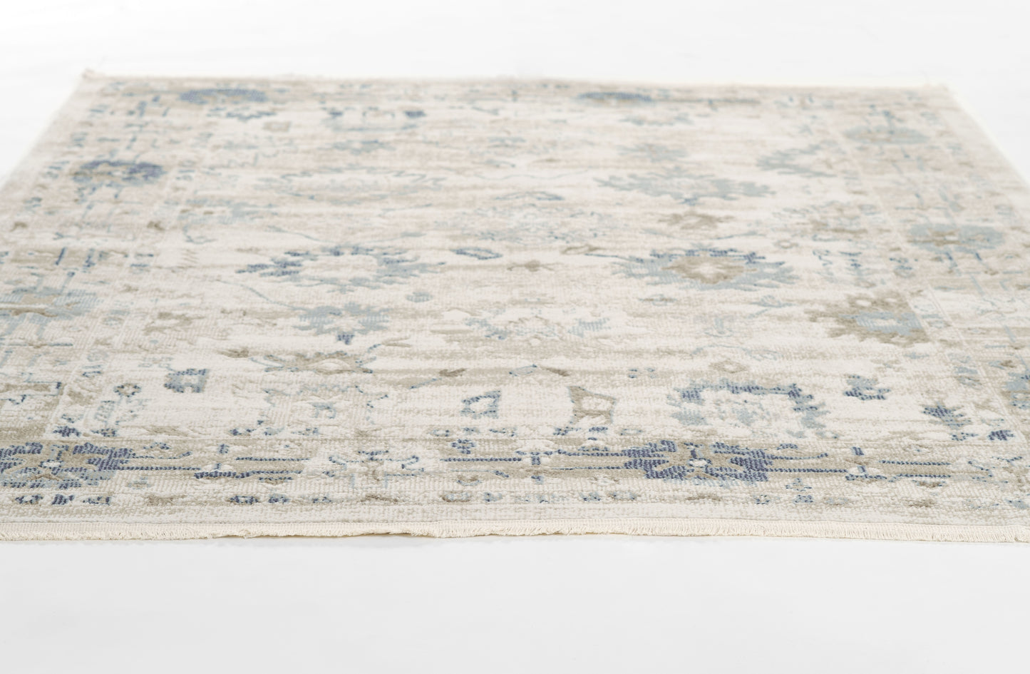 Cream & blue distressed floral area rug, rectangular with fringed border, low-pile weave.
