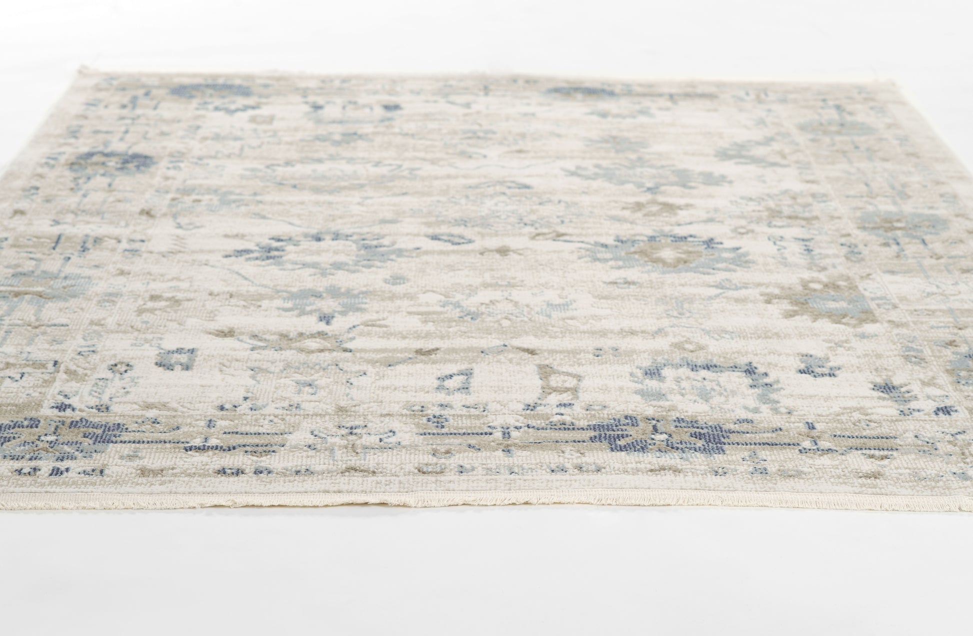 Cream & blue distressed floral area rug, rectangular with fringed border, low-pile weave.