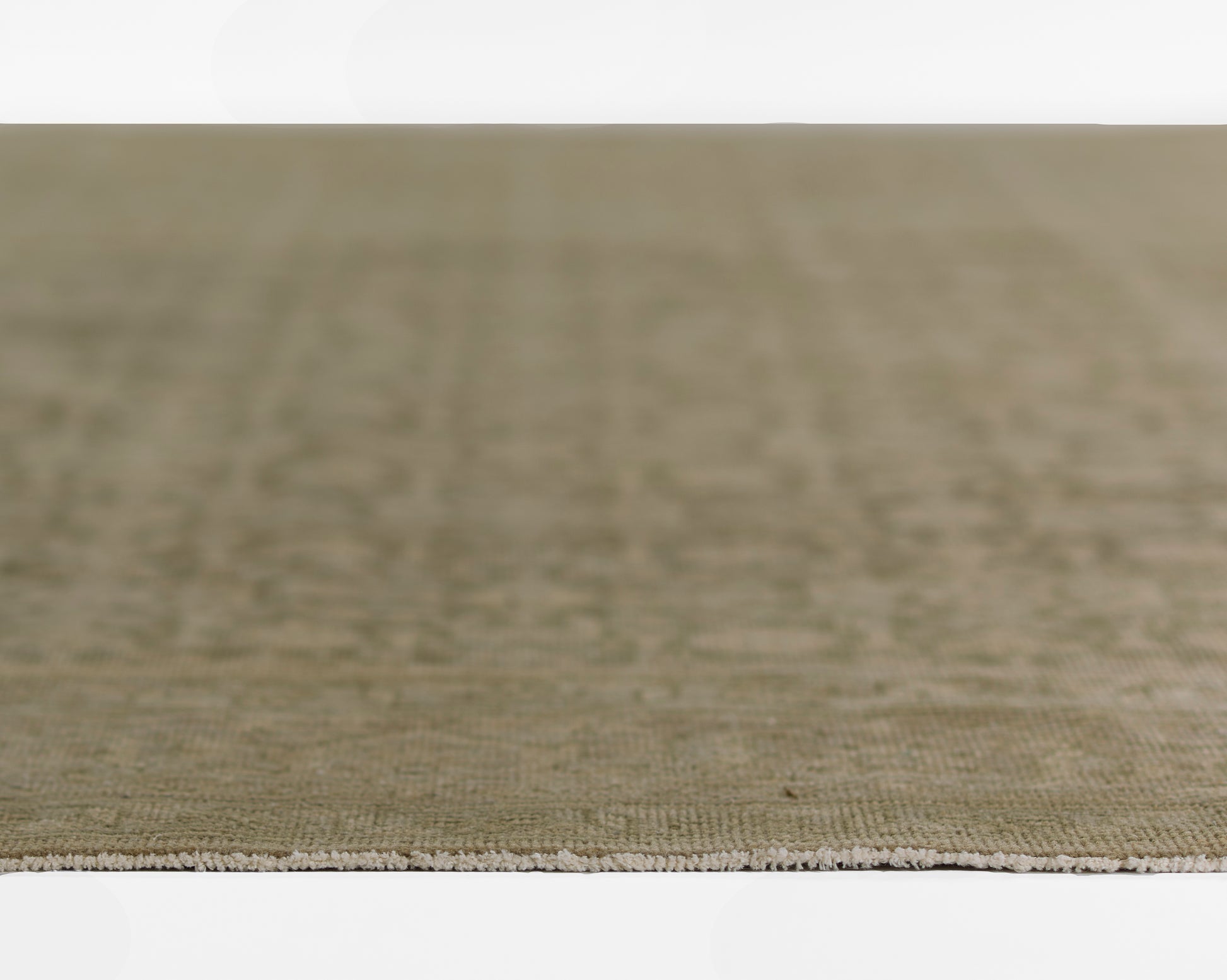 Olive-green textured rug with beige fringe along the edge; rectangular flat-weave, 9' x 12', for living room decor.