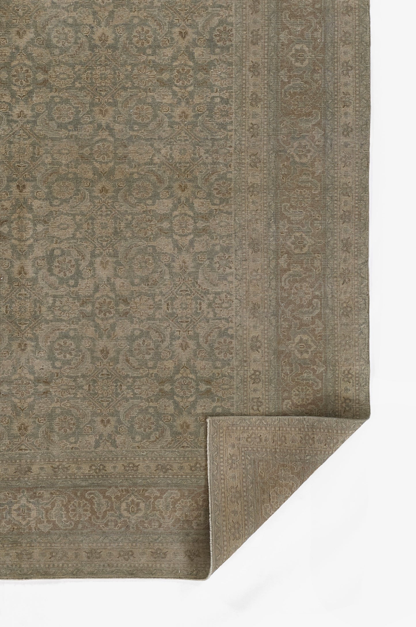 Muted blue-gray and beige Persian-style area rug with ornate floral border; woven texture, folded corner shows back.