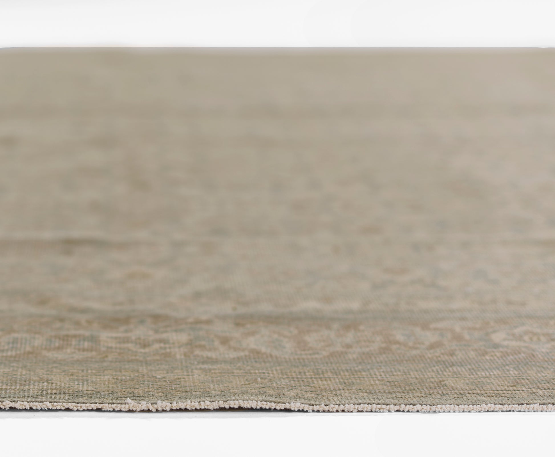 Beige flat-weave rug with subtle texture and short fringe along the edge, close-up view