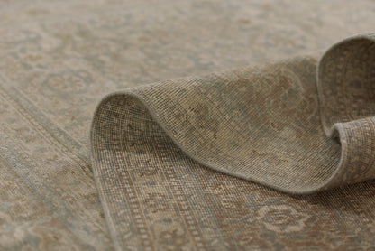Beige-toned oriental rug with subtle blue-gray motifs; woven texture, rolled edge shows soft, durable flooring.