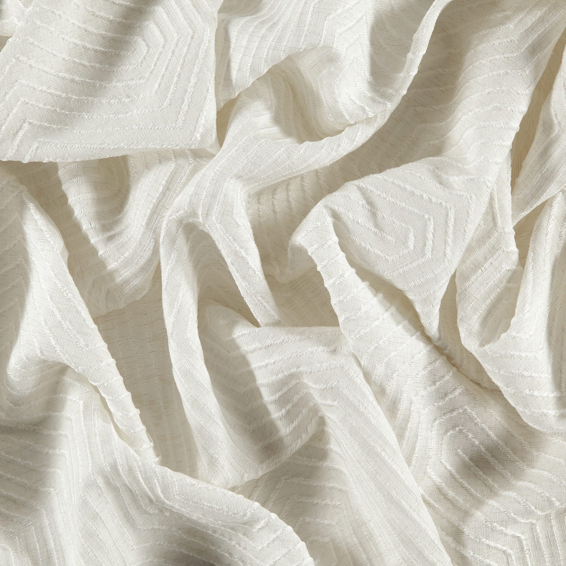 Cream jacquard fabric with geometric texture and raised chevron pattern; soft draped folds; lightweight.