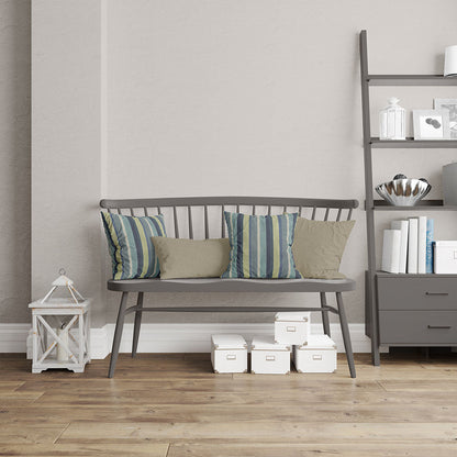 Grey wooden bench with a slatted back, striped teal-blue cushions and beige pillows, beside a grey shelving unit on a wood floor.