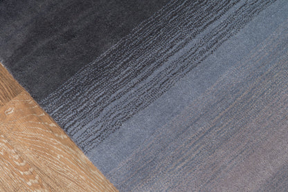 Rectangular woven rug with charcoal-to-blue gradient and subtle striped texture for modern living spaces.