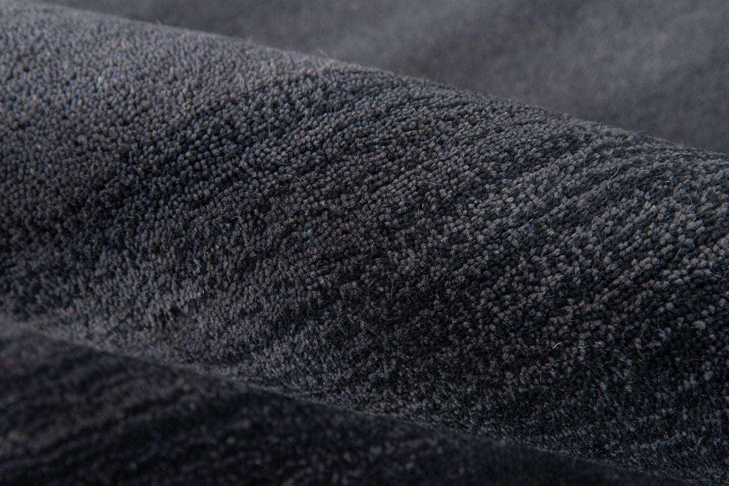 Close-up of dark charcoal plush velvet fabric with soft nap.
