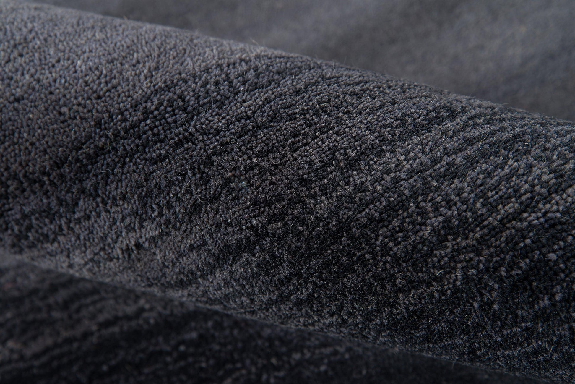 Close-up of dark charcoal plush velvet fabric with soft nap.