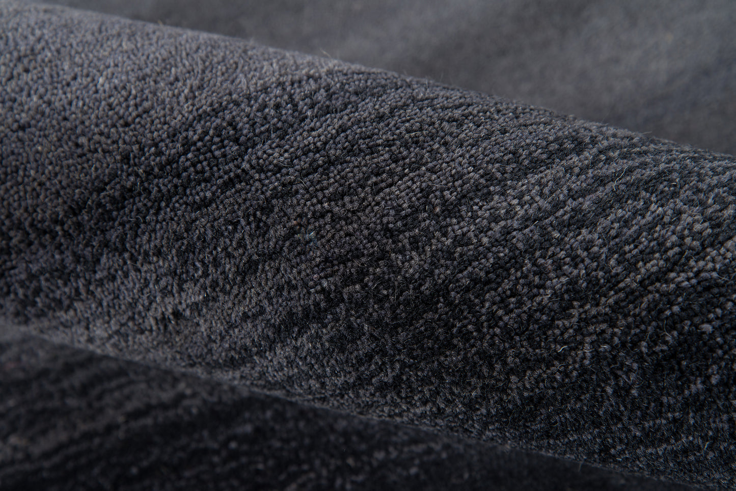 Close-up of charcoal velvet fabric with plush nap, dark soft texture for jackets or upholstery.