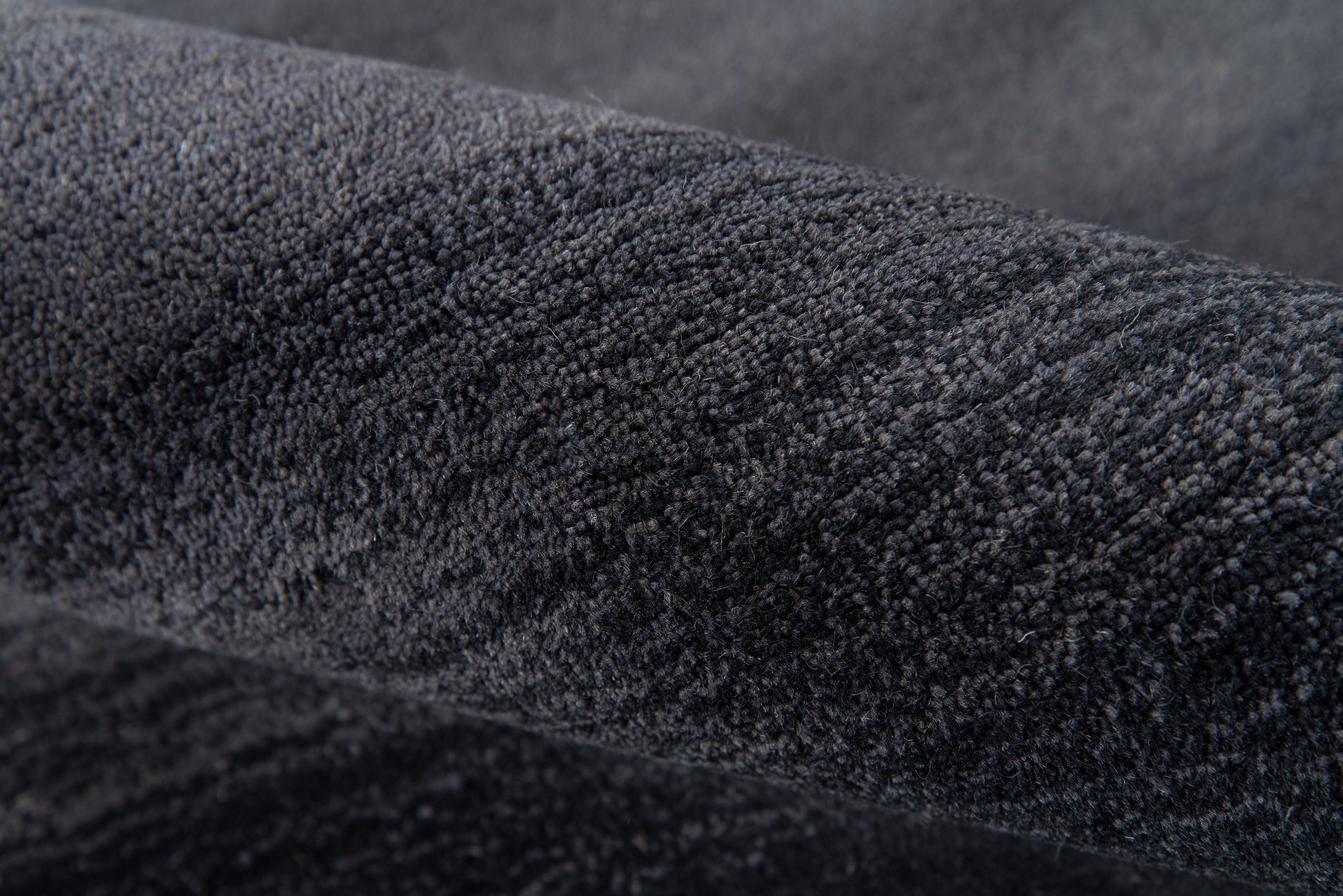 Close-up of charcoal velvet fabric with plush nap, dark soft texture for jackets or upholstery.