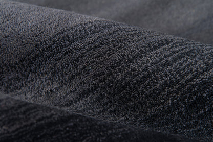 Close-up of charcoal velvet fabric with plush nap, dark soft texture for jackets or upholstery.