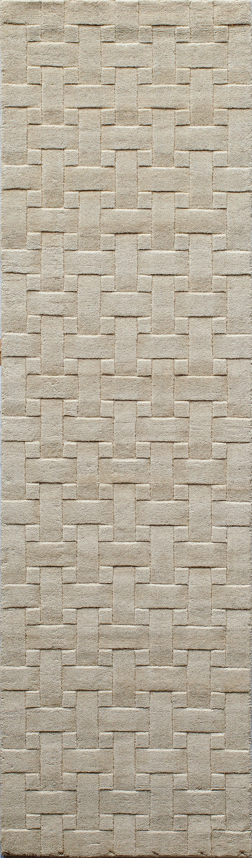 Beige woven rug with interlocking rectangular basket-weave pattern and soft textured pile.