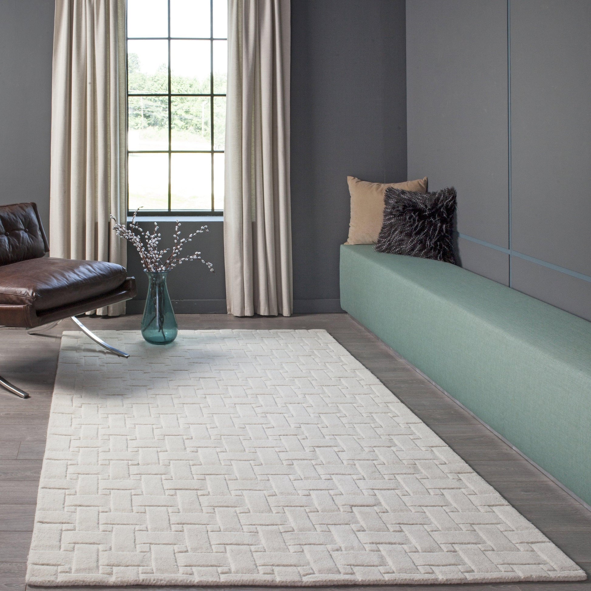 Ivory geometric runner rug on dark wood floor (2' x 8') in a modern living room with teal bench, brown leather chair, and beige curtains.
