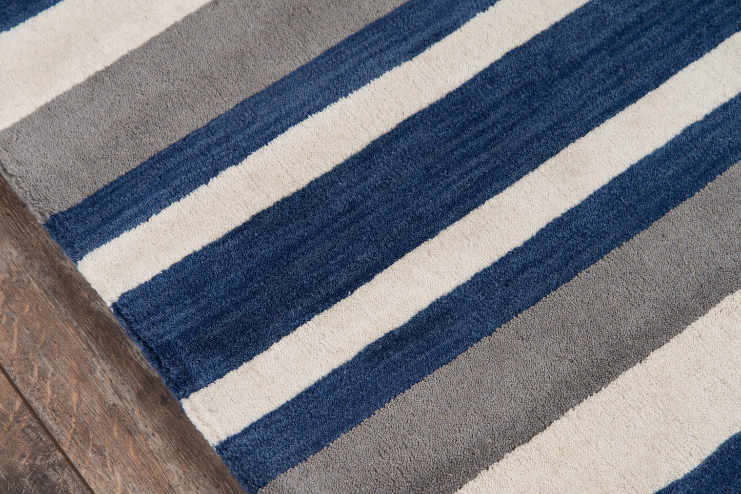 Striped 2' x 8' runner rug with navy, royal blue, beige and gray on wood floor.