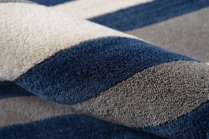 Close-up of a plush striped rug in navy, gray and beige with dense shag pile.