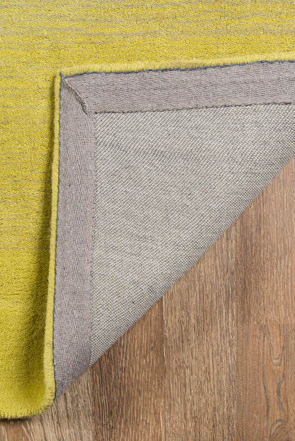 Lime yellow textured rug folded to reveal lavender-grey underside with purple edge on wood floor.