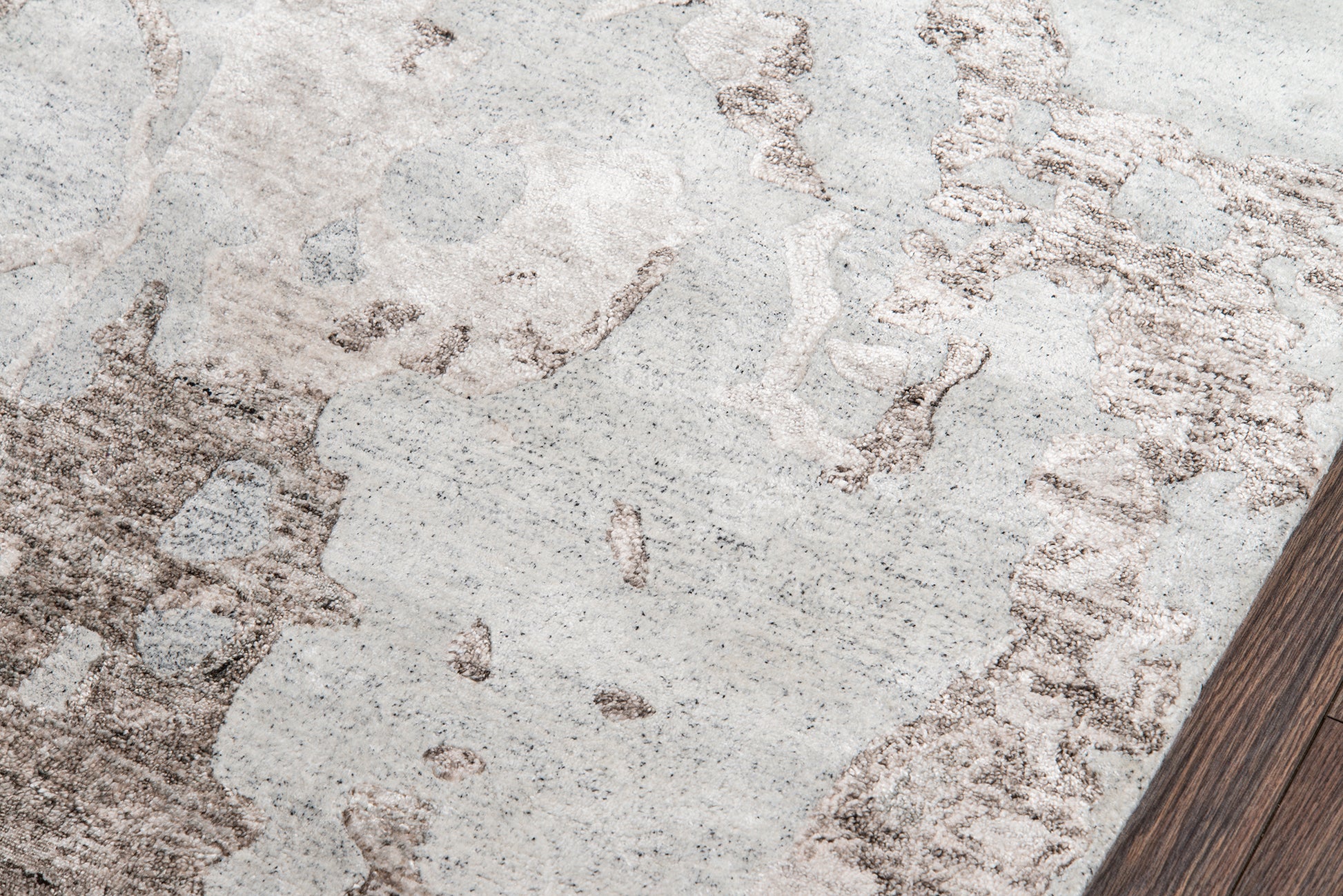 Light gray area rug with beige-brown abstract pattern on dark wood floor, 4' x 6'.