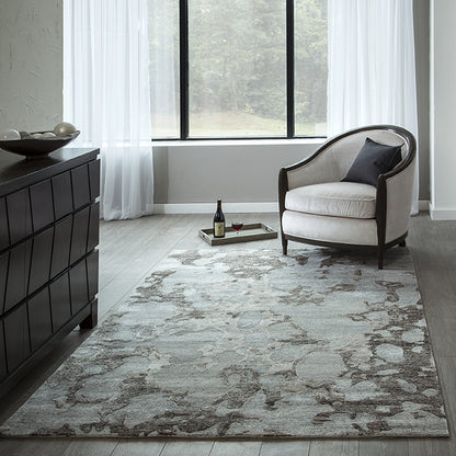 Neutral living room with a curved-back cream armchair, dark wood frame, abstract gray rug, and black dresser.