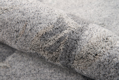 Grey shag rug, rolled view showing soft plush high-pile texture in mottled light and dark grey tones.