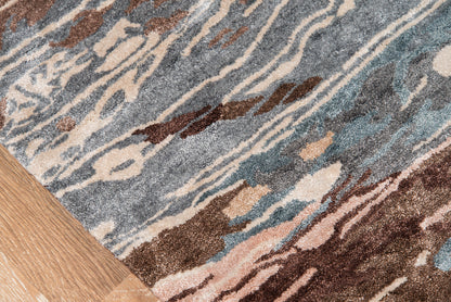 Abstract blue, beige & brown rug with flowing wave patterns; wood floor edge visible.
