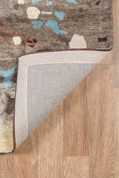Brown-gray patterned area rug with blue, teal and yellow accents; beige herringbone underside; brown edge trim.