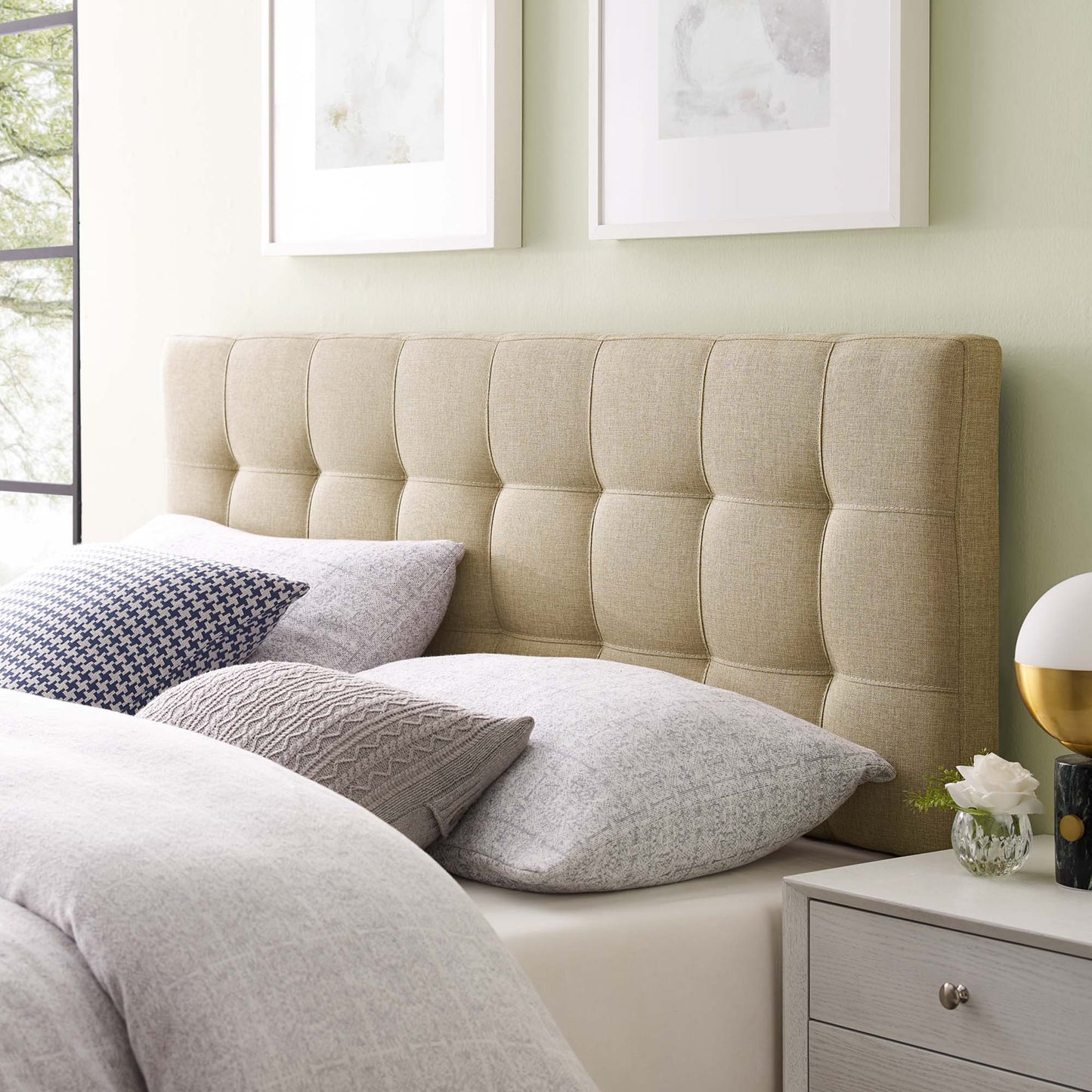 Brown tufted fabric headboard with light gray bedding & neutral pillows in a modern bedroom.