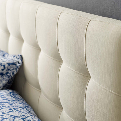 White tufted fabric full headboard with square panels; plush upholstery and blue patterned pillows on bed.