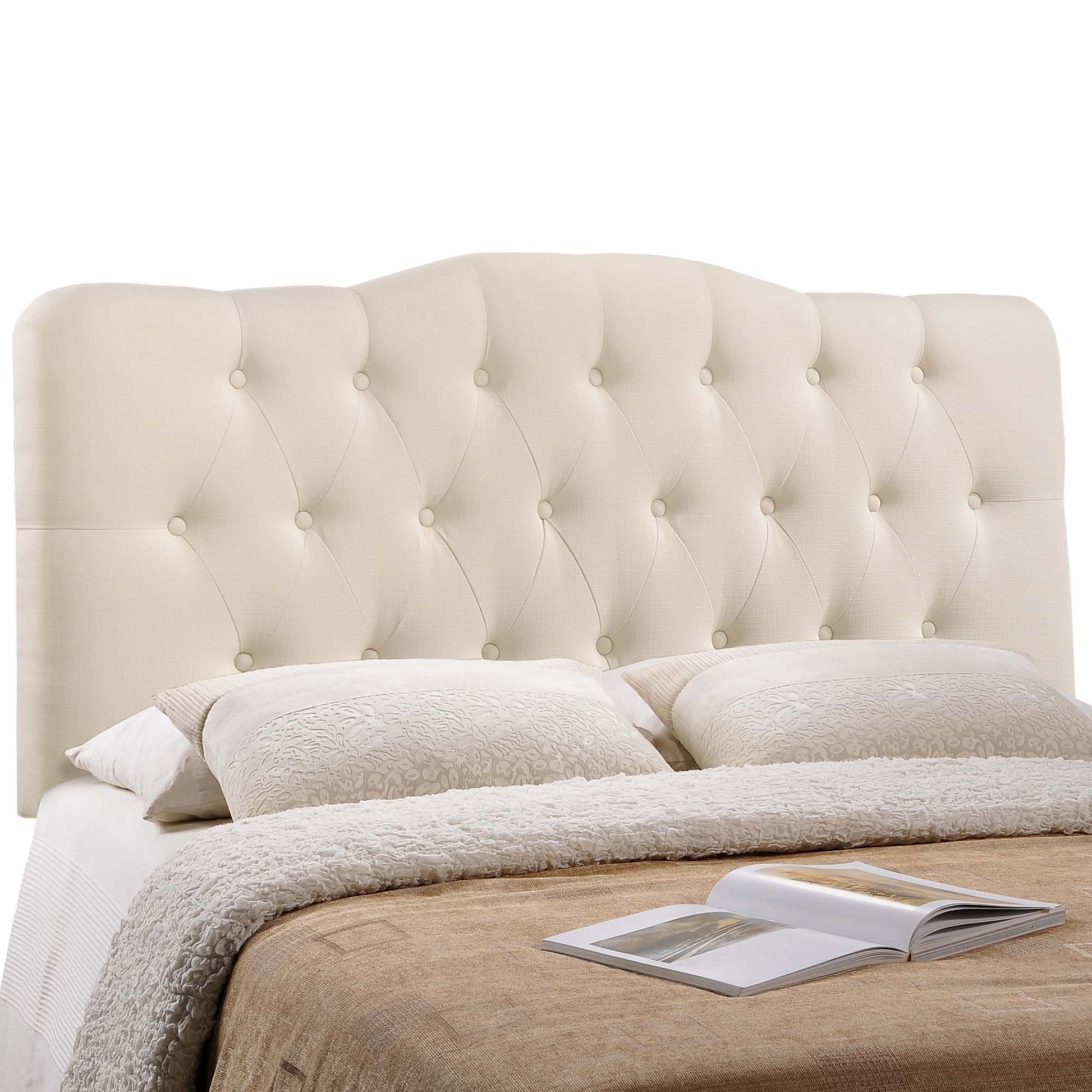White tufted upholstered headboard with a tall, button-tufted design, beige bedding, and an open magazine.