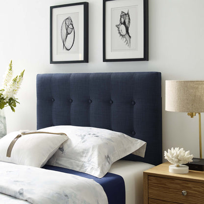 Navy tufted upholstered twin headboard with white-and-blue bedding; two framed botanical prints above; wood nightstand with lamp.