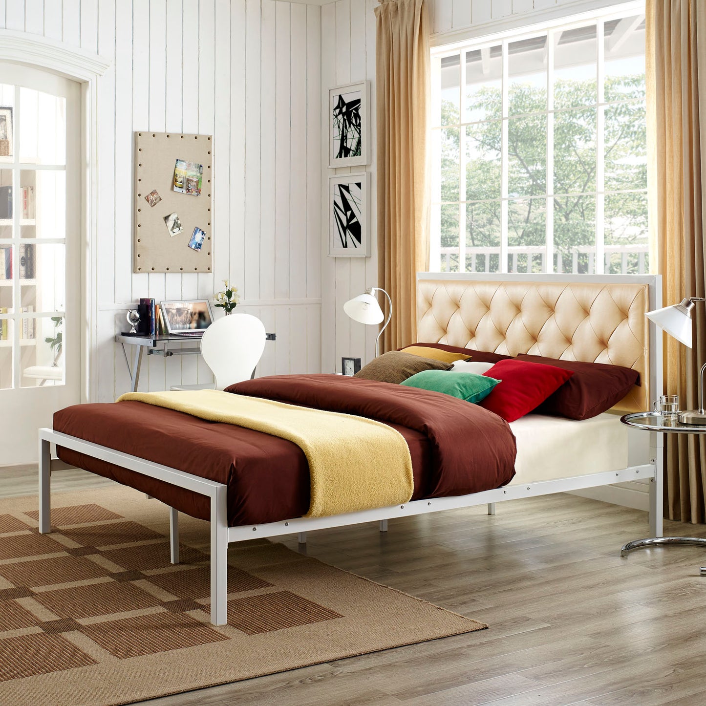 Vinyl queen bed with a tufted headboard in white champagne finish, brown comforter, yellow throw, and colorful pillows in a modern bedroom setup.