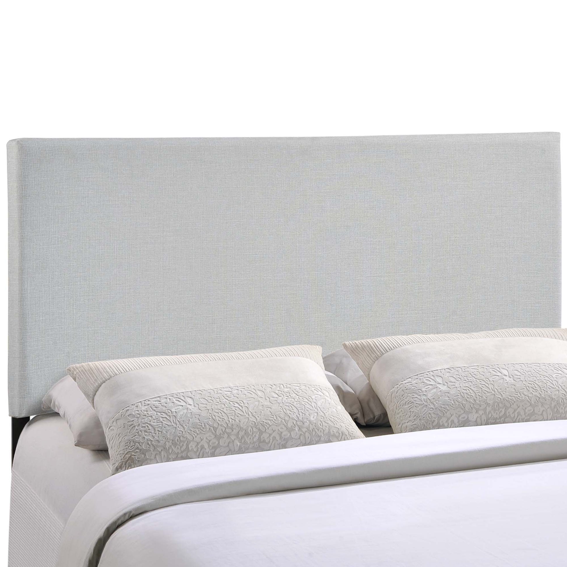 Gray upholstered headboard with two textured light-gray pillows atop white bedding.