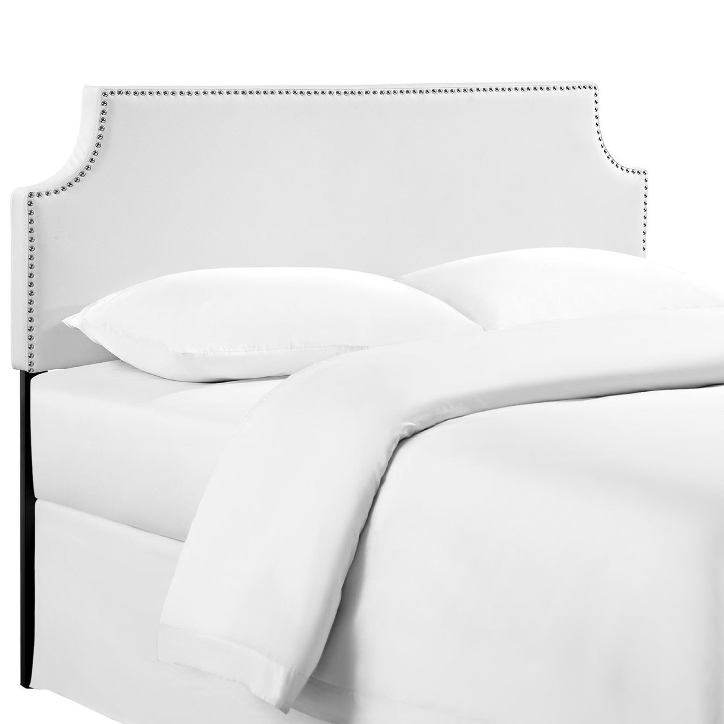 White upholstered headboard with nailhead trim and curved silhouette atop a white bed with fluffy pillows and duvet