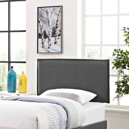 Dark gray upholstered headboard in a bright modern bedroom with white bedding, framed art, and blue and yellow vases.