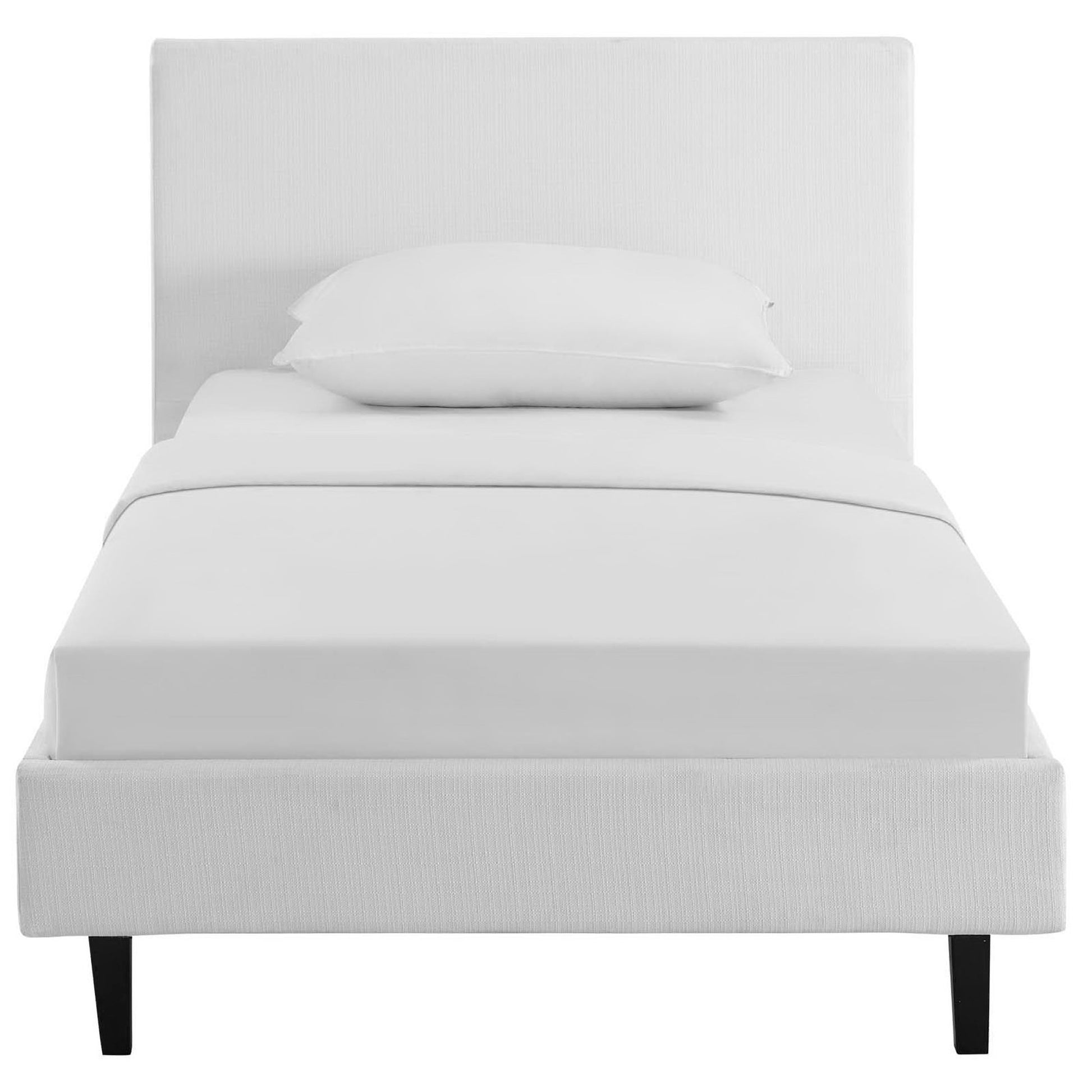 White upholstered platform bed with tall rectangular headboard, white bedding and single pillow, black tapered legs