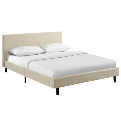 Beige upholstered platform bed with padded headboard, white bedding, and slim black legs.