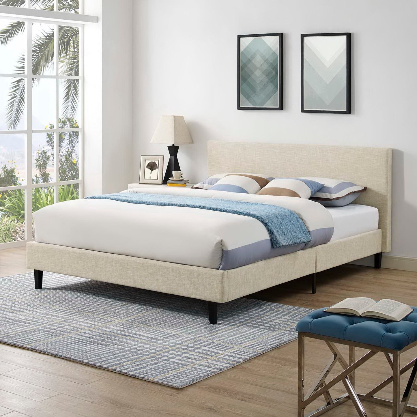 Brown upholstered platform bed with white/blue bedding and blue throw; nightstand lamp, art, blue tufted bench.