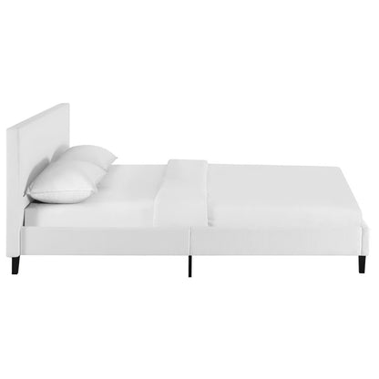 White upholstered platform bed with tall headboard, two pillows, minimalist modern design.