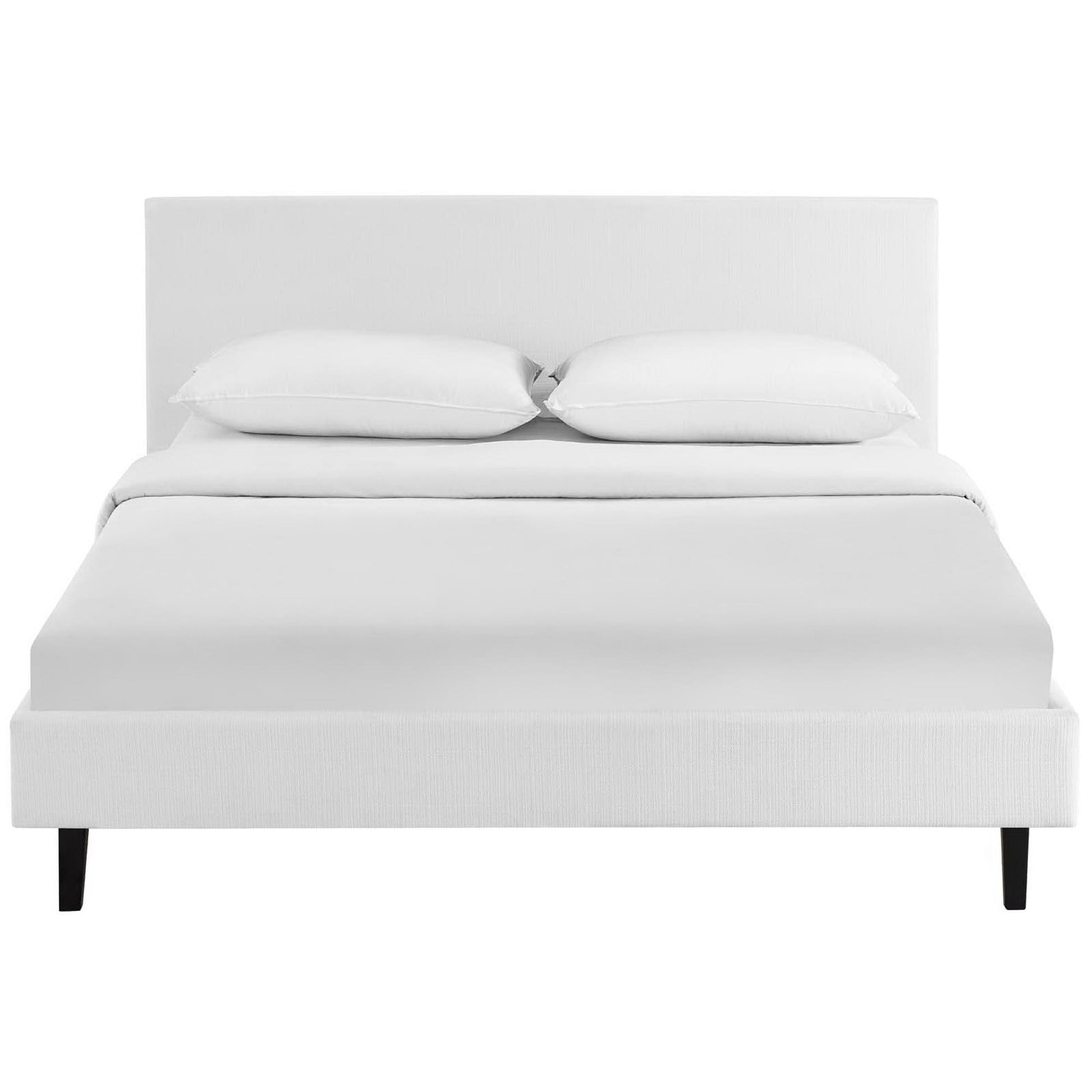 White upholstered platform bed with a rectangular headboard, black tapered legs, and crisp white bedding.