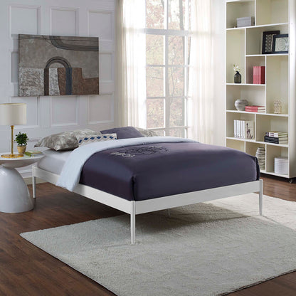 White metal full bed frame with a navy duvet, light gray rug, tall white bookshelf, and large gray abstract wall art.