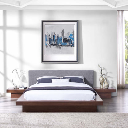 Walnut platform bed with gray upholstered headboard, white and navy bedding, and abstract blue cityscape art.