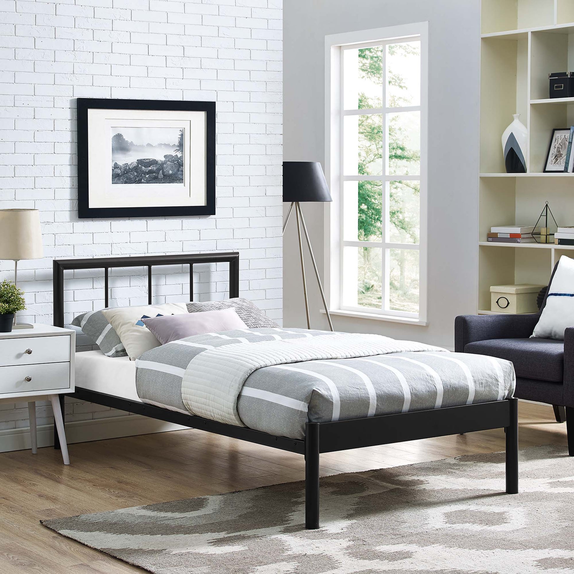Brown metal twin bed frame with a gray-and-white striped comforter, white nightstand, and a modern lamp in a bright, cozy bedroom.