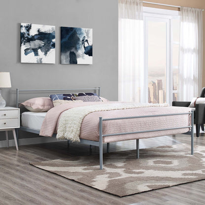 Gray metal platform bed with pink quilt, cream throw, gray walls, abstract navy art, nightstand, and rug in a modern bedroom.
