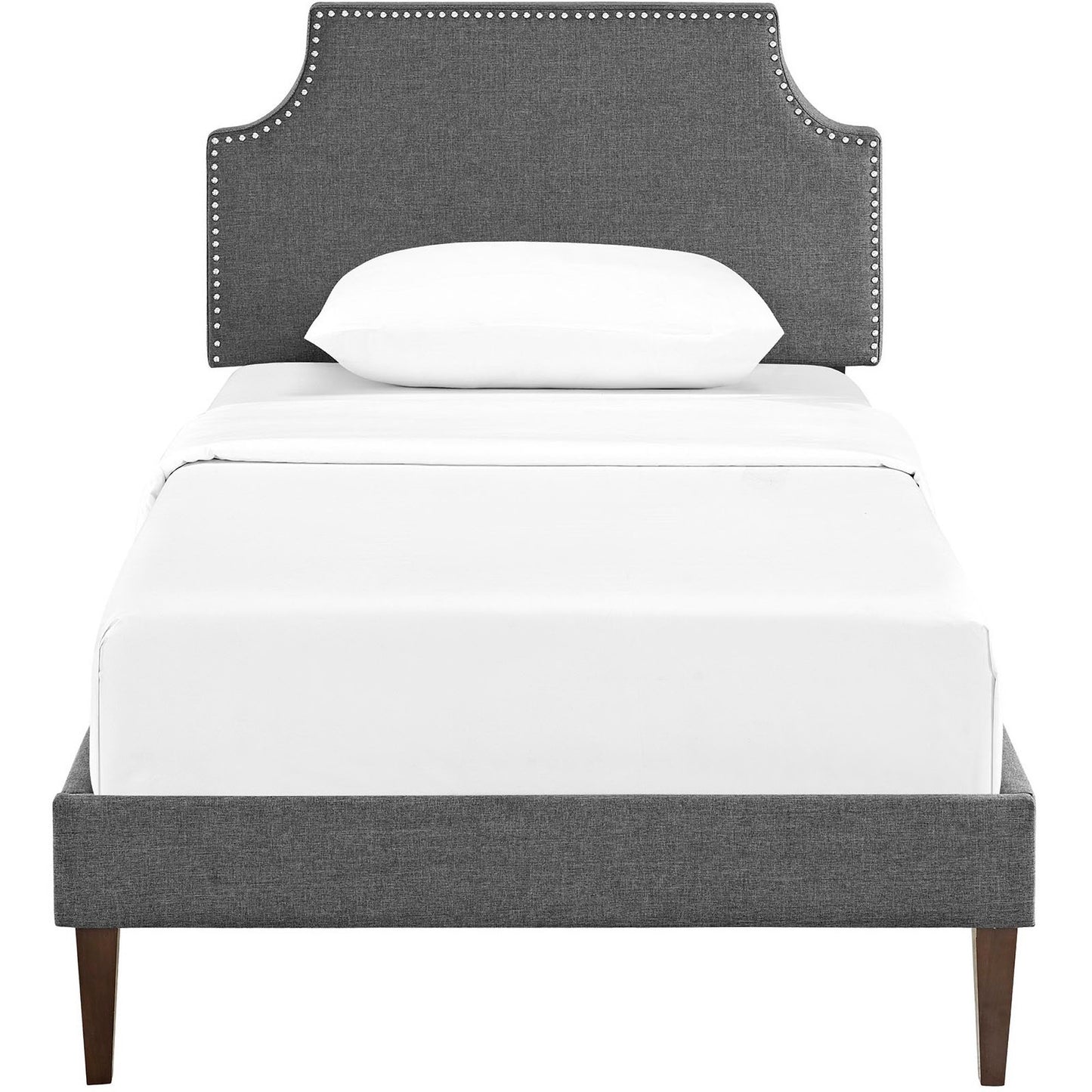Grey upholstered twin platform bed with squared tapered legs and a studded headboard, topped with white bedding.
