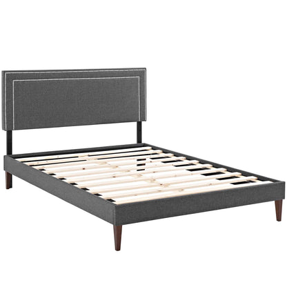 Gray fabric upholstered platform bed with padded headboard, wooden slats, tapered legs; modern minimalist style.