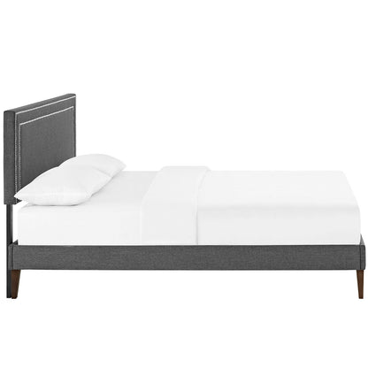 Gray upholstered platform bed with tall stitched headboard, white bedding, and tapered wooden legs.